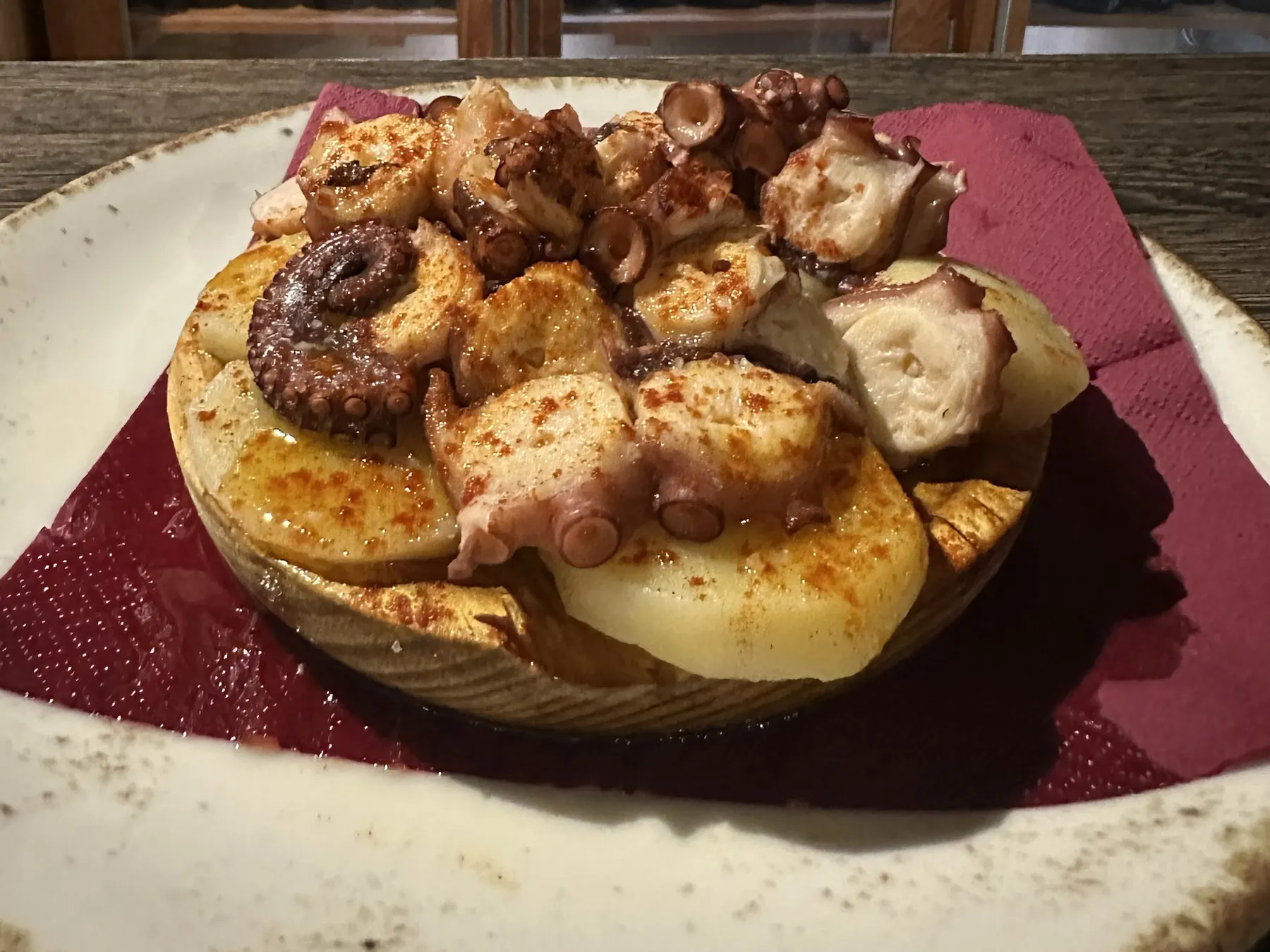 Pulpo á feira en plato de madera: rodajas de pulpo cocido sobre cachelos, con pimentón y aceite de oliva por encima