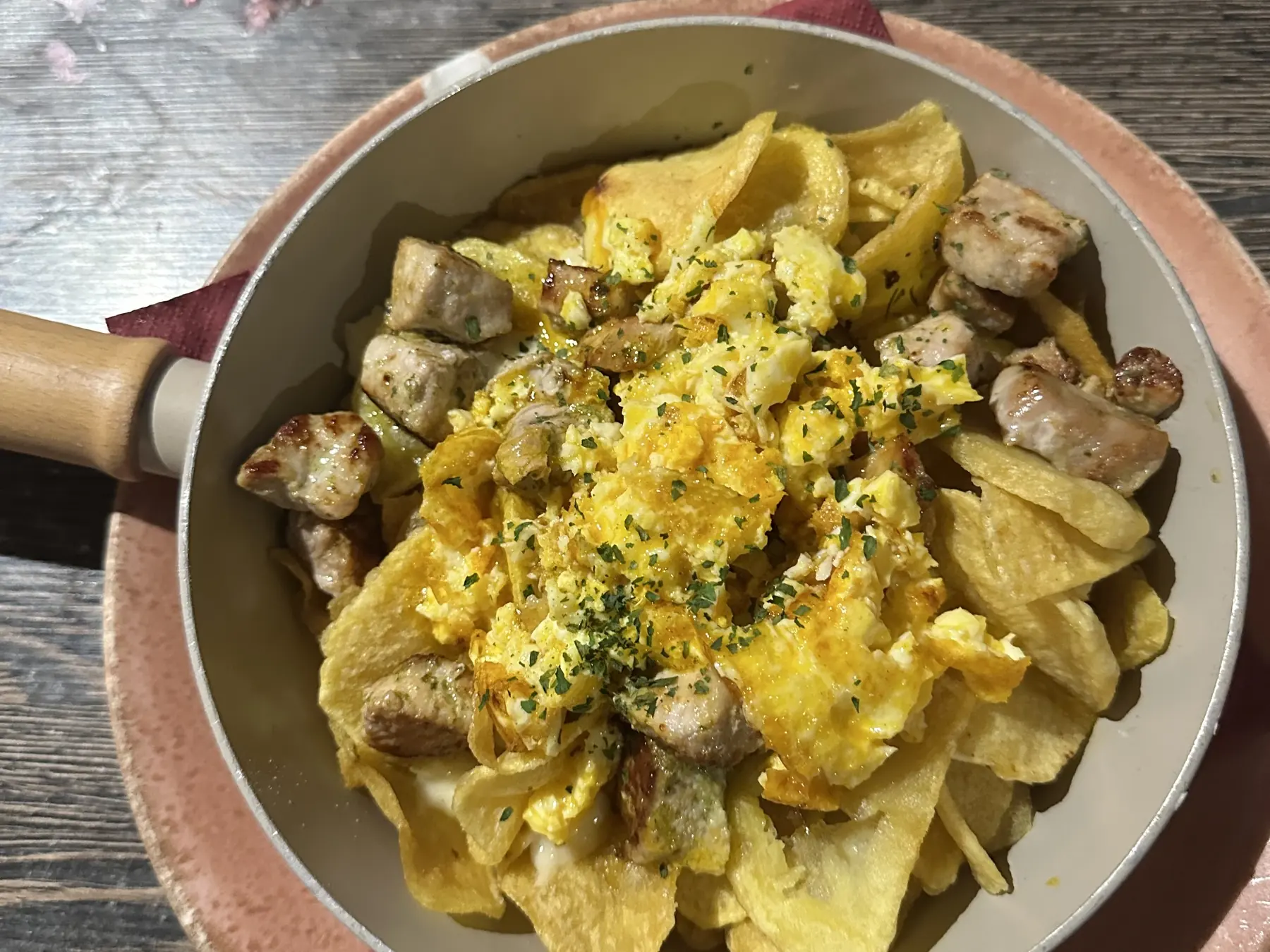 Tixola de raxo con queso de Arzúa vista desde arriba: sartén con patatas, tacos de raxo y huevo cuajado, sobre la mesa de Tixola Tapería
